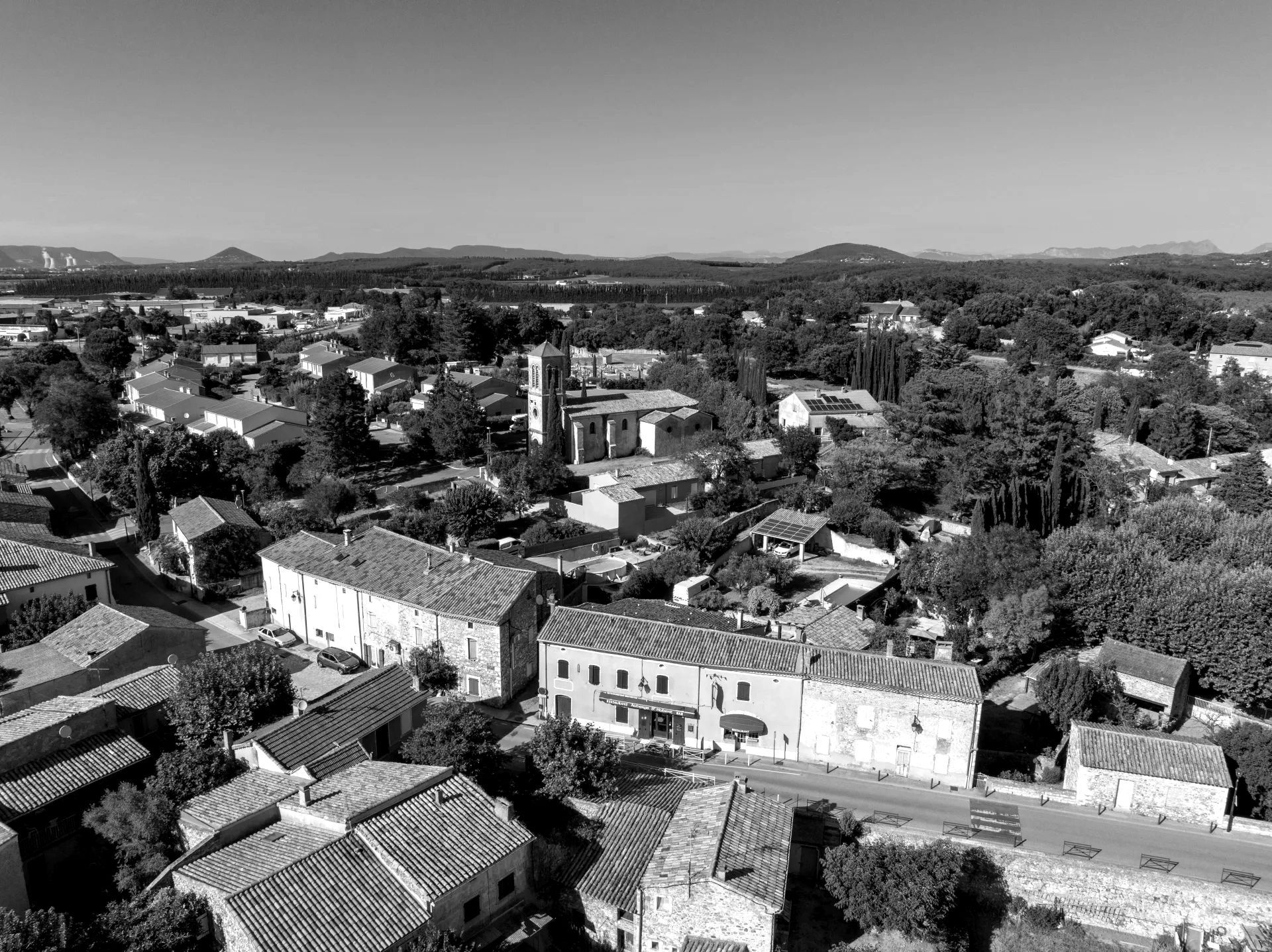 Vue aérienne du village de Malataverne, ses toits de tuiles et son église, avec les collines de la Drôme à l’horizon